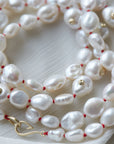 Baroque white freshwater pearl necklace with coral-hued silk and gold clasp by Hannah Blount