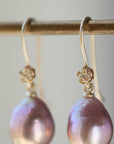 detail shot of pink pearl drop earrings with 14k yellow gold ear wires with rose accents.