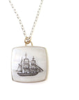 a square mother of pearl slice is set in silver with a gold ring and silver chain. An old whaling ship is hand etched into the surface with black ink, called scrimshaw.