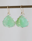 Pair of green teardrop earrings on a thin rod against a light background