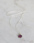Silver necklace with a purple gemstone pendant on a light gray background