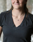 woman wearing dark grey shirt with purple pendant necklace