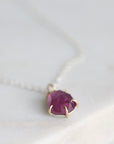 Necklace with a drop-shaped purple gemstone on a white background