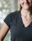 dark grey shirt with purple pendant necklace