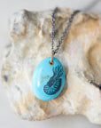 kingman turquoise pendant with inked illustration of a nautilus on oxidized silver chain with gold details