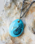 kingman turquoise pendant with inked illustration of a nautilus on oxidized silver chain with gold details