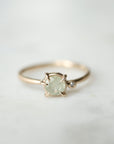 white sapphire set in a gold ring with a single white diamond on the side