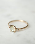 side view white sapphire set in a gold ring with a single white diamond on the side