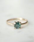 teal montana sapphire set in gold prongs on a gold ring