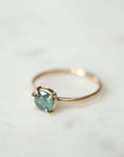 side view of teal montana sapphire set in gold prongs on a gold ring