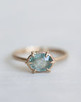 14k yellow gold ring with a light blue Montana sapphire on a soft white fabric background.