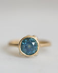 Gold ring with a blue gemstone on a light gray background