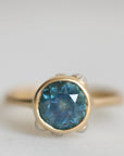 Gold ring with a blue gemstone on a light gray background