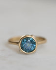Gold ring with a blue gemstone on a light gray background