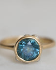 Gold ring with a blue gemstone on a light gray background