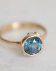 Gold ring with a blue gemstone on a light gray background