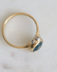 Gold ring with a blue gemstone on a light gray background