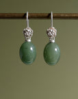 sage green jade oval beads hang beneath silver ear wires featuring little silver roses on them