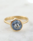periwinkle sapphire set in a yellow gold ring with three white gold barnacles with diamonds. Front view.