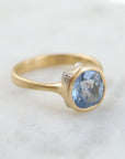 periwinkle sapphire set in a yellow gold ring with three white gold barnacles with diamonds. 1/4 view.