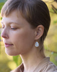 Woman wearing earrings with a blurred natural background