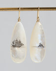 Teardrop-shaped mismatched earrings, a ship design on one and a mermaid on the other.
