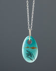 kingman turquoise bead with hand scrimshaw in ink. Pendant necklace with bright silver chain with gold egg link.