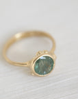 Gold ring with a green gemstone on a light fabric background