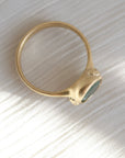 Gold ring with a green gemstone on a textured white surface