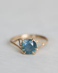 Gold ring with a blue gemstone on a light gray background