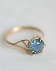 Gold ring with a blue gemstone on a light fabric background