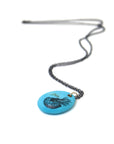 kingman turquoise pendant with inked illustration of a nautilus on oxidized silver chain with gold details