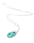 kingman turquoise bead with hand scrimshaw in ink. Pendant necklace with bright silver chain with gold egg link.
