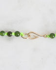 Green beaded necklace with a gold clasp on a white background