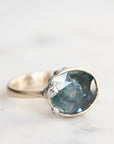 Ring with a large blue gemstone and smaller diamonds on a light background
