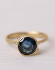 Gold ring with a dark gemstone on a white fabric background
