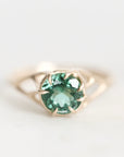 A gold ring featuring a round-cut green gemstone in a prong setting, photographed on a clean white background.