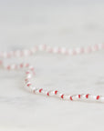 Necklace with red and white beads on a light gray background