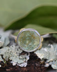 Ring with a green Montana sapphire stone on a lichen-covered branch