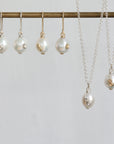 A jewelry set featuring white freshwater pearls with small gold and clear crystal accents, displayed on a gold-colored rod with matching drop earrings and necklaces.