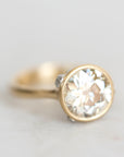 Gold bezel set diamond ring with platinum barnacle accent photographed against a white background.