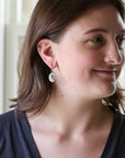 Woman wearing white drop earrings.