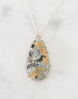 Necklace with a teardrop-shaped pendant on a light gray background