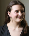 Woman wearing large earrings with a neutral background