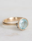 Gold ring with a light blue gemstone on a white background