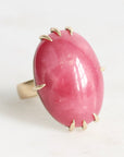 Ring with a pink stone and gold accents on a white background