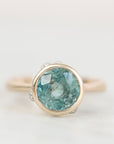 Bezel set ring with blue green stone with inclusions.