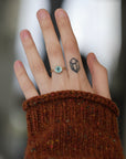 Hand wearing blue gemstone ring.