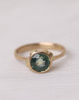 Gold ring with a green gemstone on a white fabric background