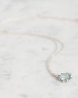 Necklace with a light blue gemstone on a marble surface